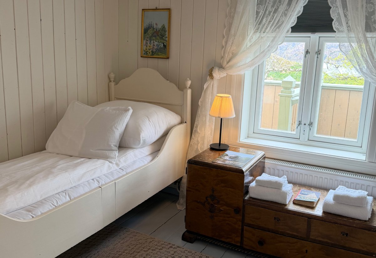 Enkelt soverom med hvitt sengetøy.